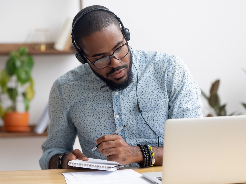 man listening to podcast and transcribing