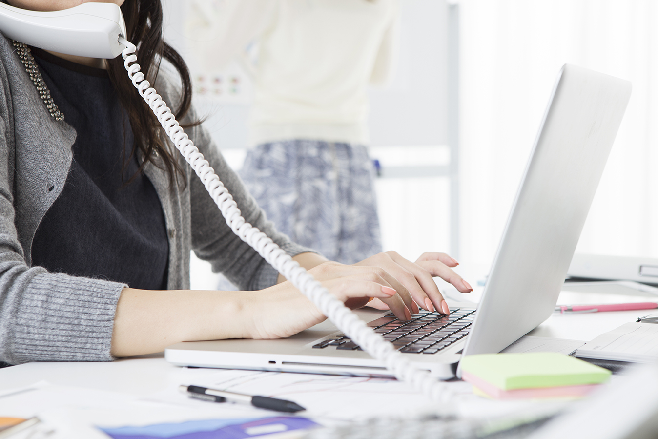 woman on the phone and typing on laptop